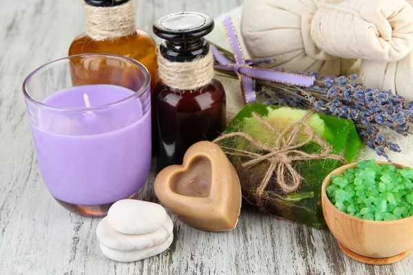 Still life with lavender candle, soap, massage balls, bottles, soap and fresh lavender, on wooden background — Stock Photo, Image