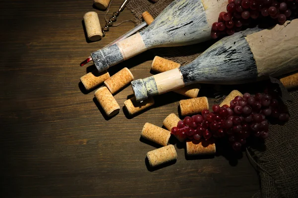 Старые бутылки вина, винограда и пробок на деревянном фоне — стоковое фото