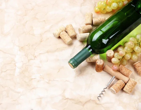 Fles wijn, druiven en kurken op oude papier achtergrond — Stockfoto