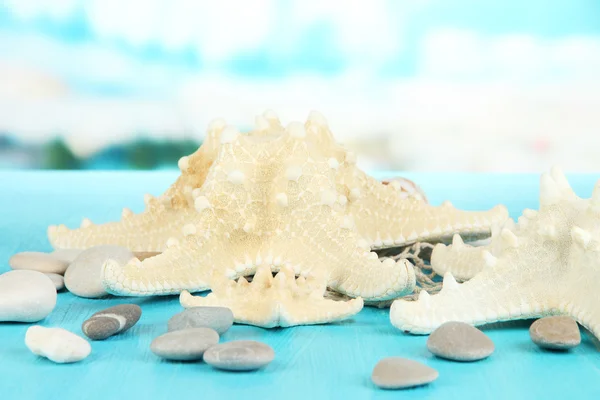 White starfishes on blue wooden table on sea background — Stock Photo, Image