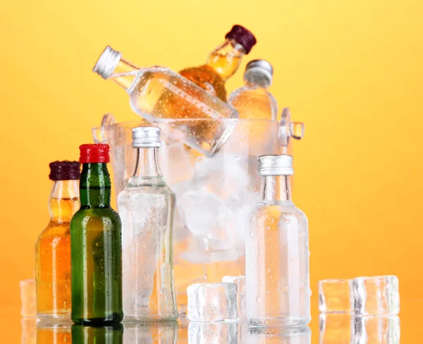Minibar flaskor i hink med isbitar, på färgbakgrund — Stockfoto