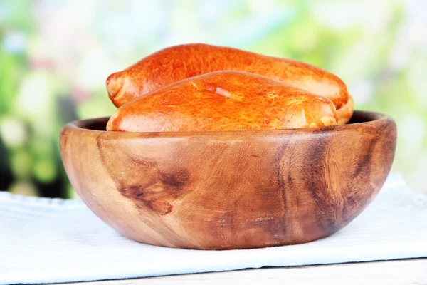 Vers gebakken pasteitjes, in houten kom, op houten tafel, op lichte achtergrond — Stockfoto