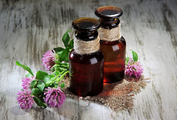 Medicine bottles with clover flowers on wooden table — Stock Photo, Image