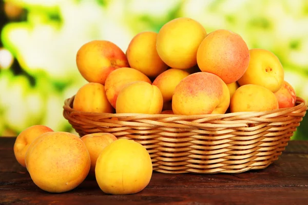 Fresh natural apricot in wicker basket on wooden table — Stock Photo, Image