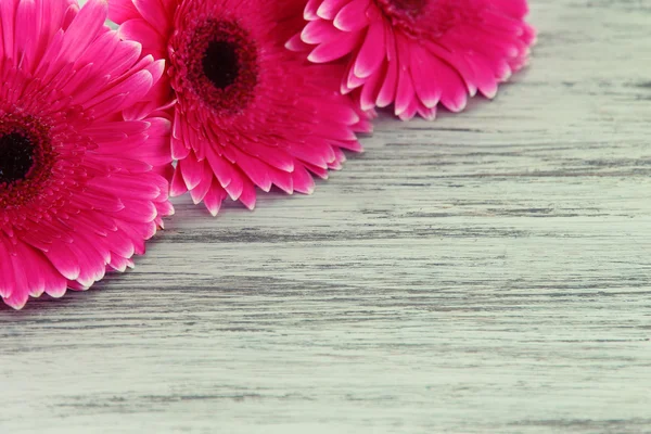 Mooie roze gerbera's op houten tafel — Stockfoto