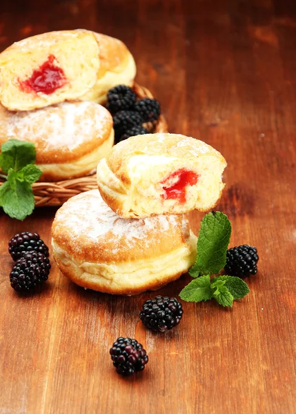 Вкусные пончики с ягодами на деревянном столе — стоковое фото