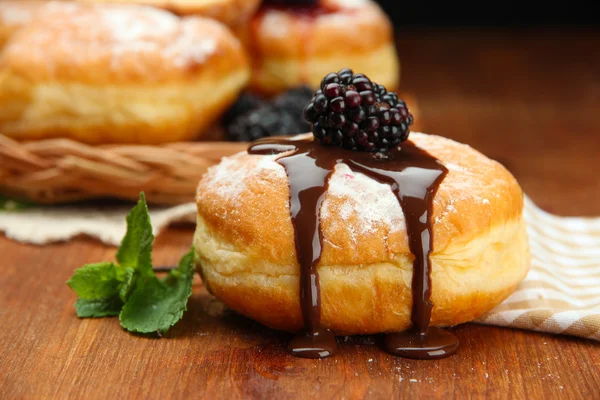 Läckra munkar med choklad och bär på träbord — Stockfoto