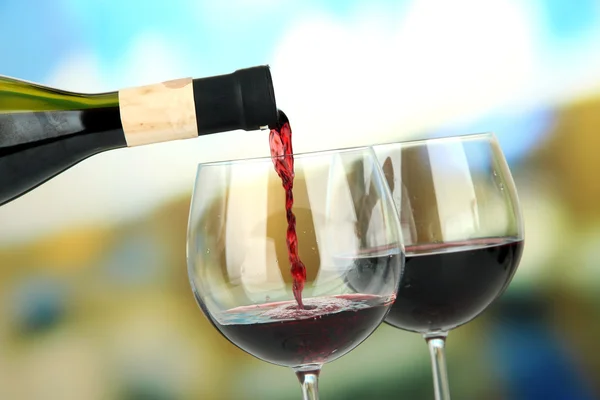 Red wine being poured into wine glass, on bright background — Stock Photo, Image