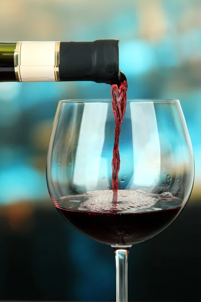 Vin rouge versé dans un verre à vin, sur fond lumineux — Photo