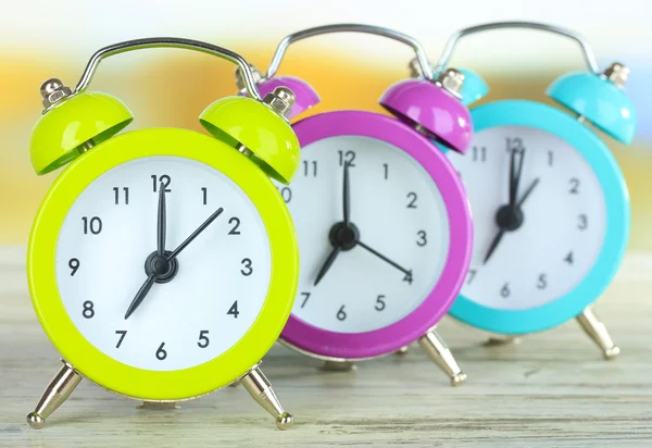Kleurrijke alarm klokken op tafel op lichte achtergrond — Stockfoto