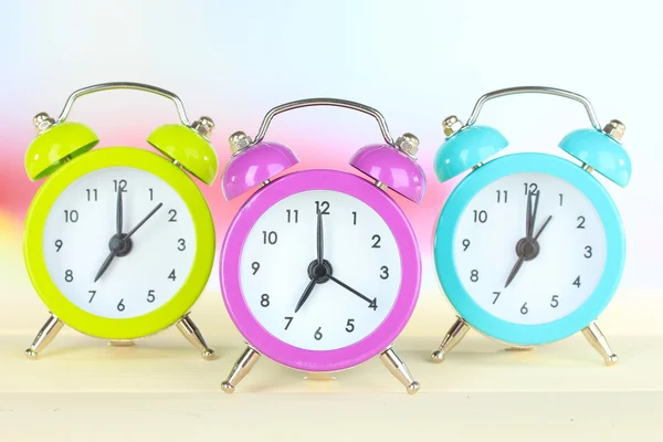 Colorful alarm clocks on table on light background — Stock Photo, Image