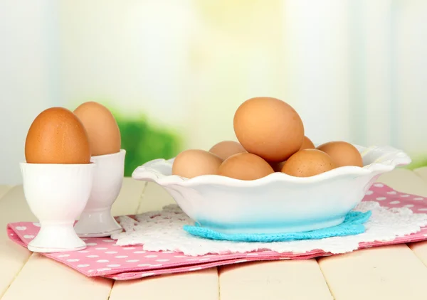 Яйца в тарелке на деревянном столе на естественном фоне — стоковое фото