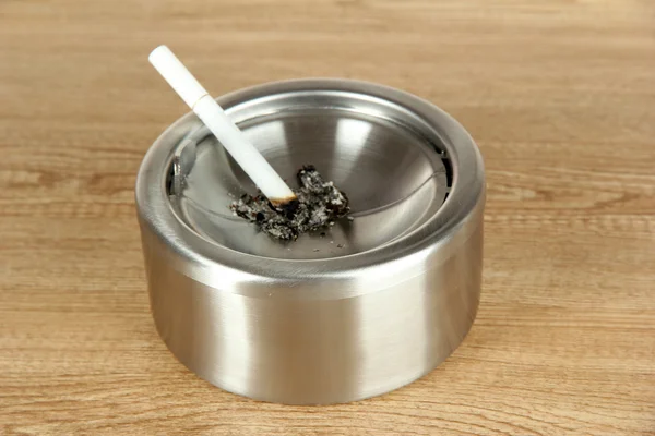 金属烟灰缸和木桌子上的香烟 — 图库照片