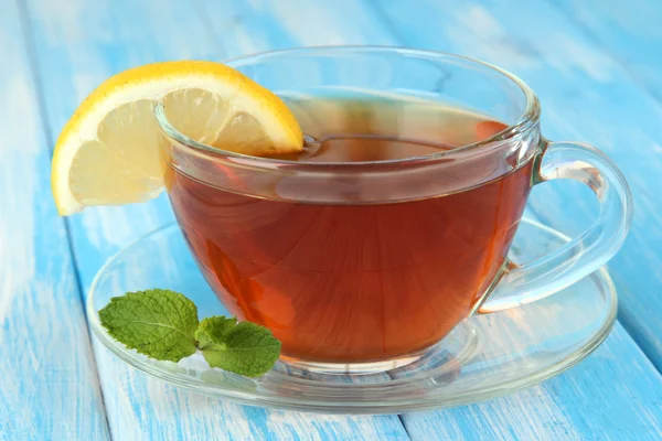 Tasse Tee mit Zitrone auf dem Tisch auf blauem Hintergrund — Stockfoto