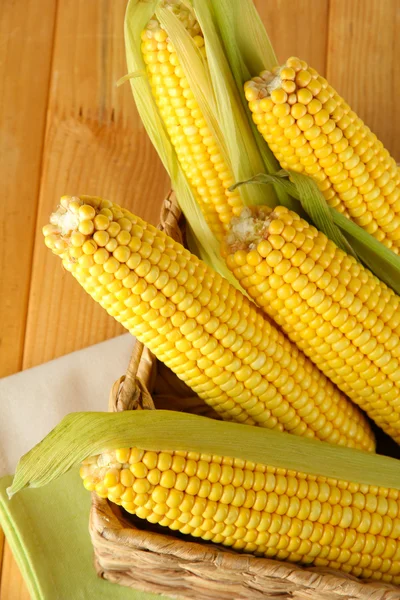 Crude corns in basket on napkin on wooden table — Stock Photo, Image
