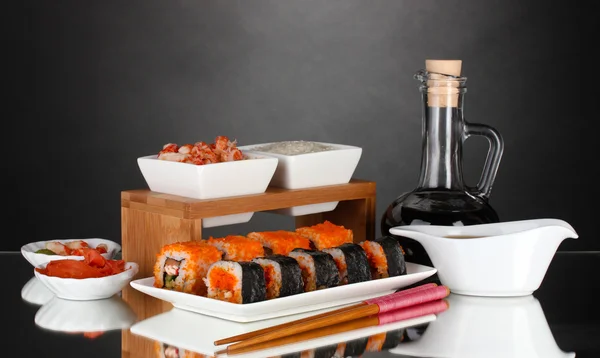 Heerlijke sushi op plaat, eetstokjes, sojasaus, vis en garnalen op grijze achtergrond — Stockfoto