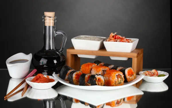 Delizioso sushi su piatto, bacchette, salsa di soia, pesce e gamberetti su sfondo grigio — Foto Stock