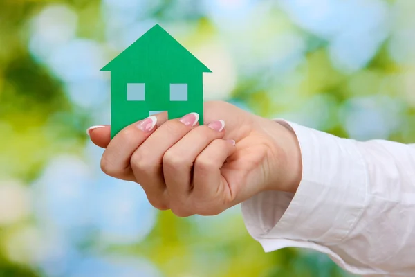 Concept: woman hand with paper house on green background, close up — Stock Photo, Image