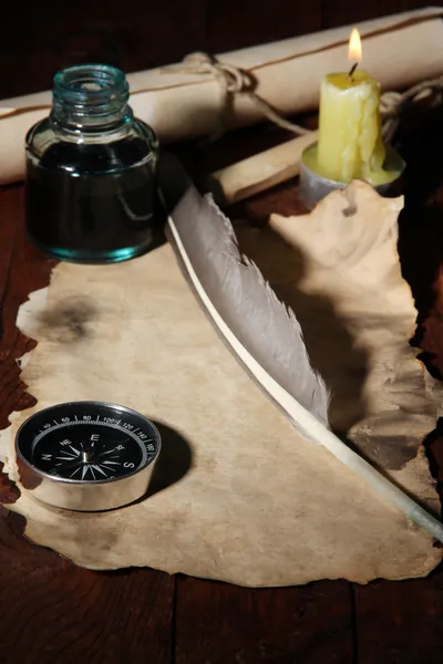 Papel velho com caneta de tinta perto da vela de iluminação na mesa de madeira — Fotografia de Stock