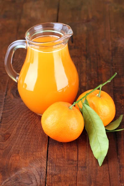 Full jug of tangerine juice, on wooden background — Stock Photo, Image