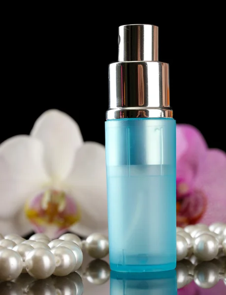 Perfume feminino em bela garrafa e flores de orquídea, no fundo preto — Fotografia de Stock