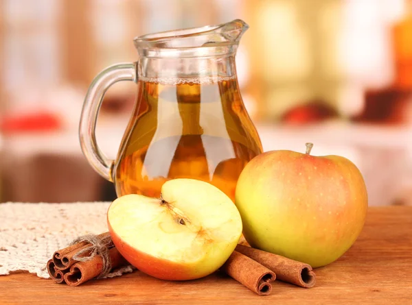 Full jug of apple juice and apple on wooden table on bright background — Stock Photo, Image