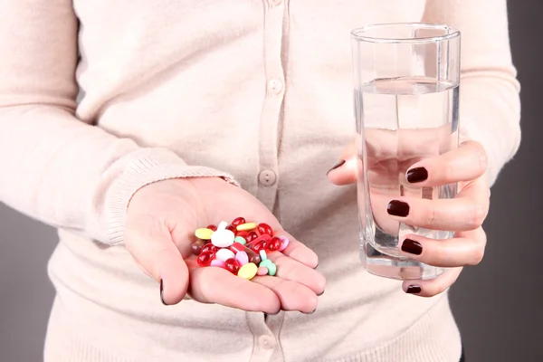 Muchas píldoras y agua de vidrio en la mano — Foto de Stock