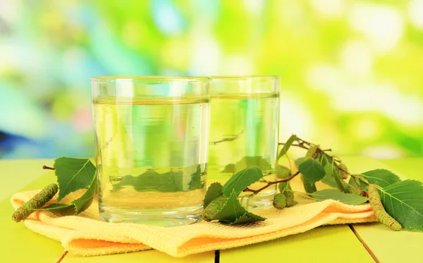 Glasses of birch sap on wooden table, on green background — Stock Photo, Image