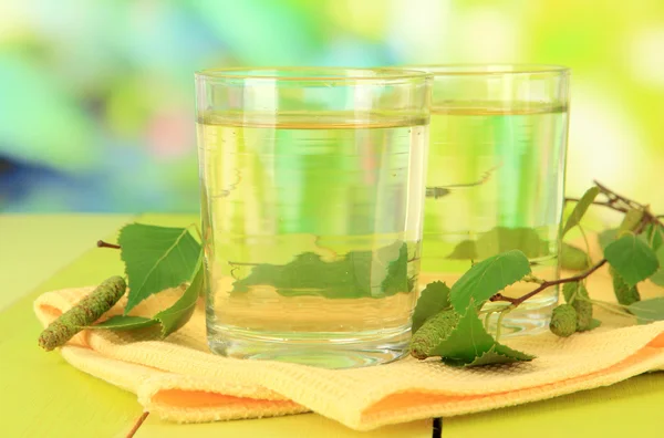 Glazen birch sap op houten tafel, op groene achtergrond — Stockfoto