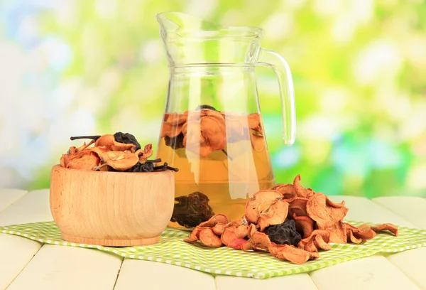 Assorted dried fruits in bowl and compote of dried fruits on wooden table on natural background — Stock Photo, Image
