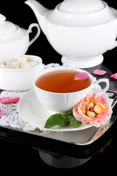 Tetera y taza de té de rosa de té en bandeja metálica sobre fondo negro servilleta — Foto de Stock