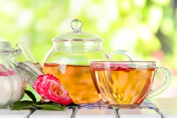 Waterkoker en kopje thee uit de thee rose op servet op houten tafel op aard achtergrond — Stockfoto