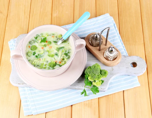 Cabbage soup in plate on napkin on board for cutting on wooden table — Stock Photo, Image