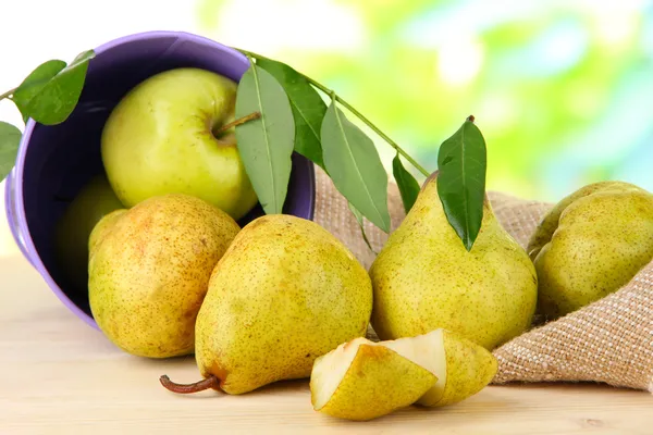 Pears in bucket on burlap on wooden table on nature background — Stock Photo, Image