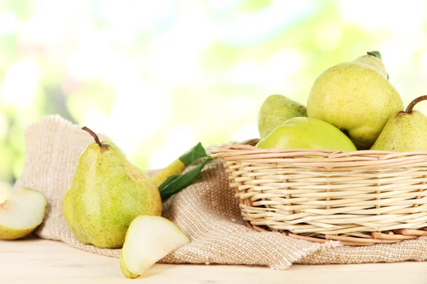 Päron i korg på säckväv på träbord på natur bakgrund — Stockfoto