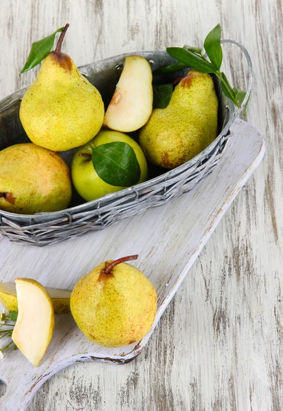 Pears in basket on board on wooden table — Stock Photo, Image