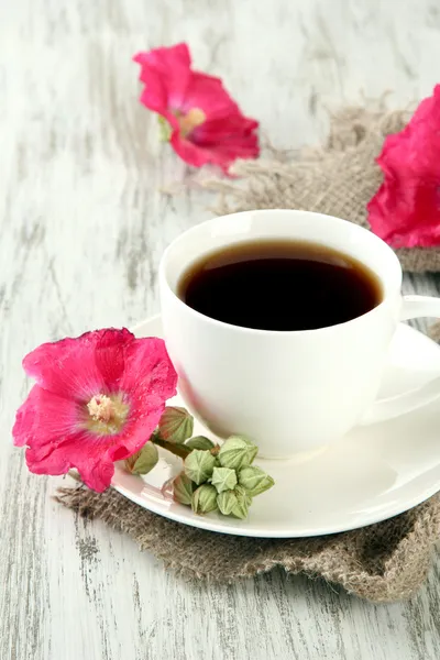 Cup of coffee and pink mallow flowers on wooden background — Stock Photo, Image