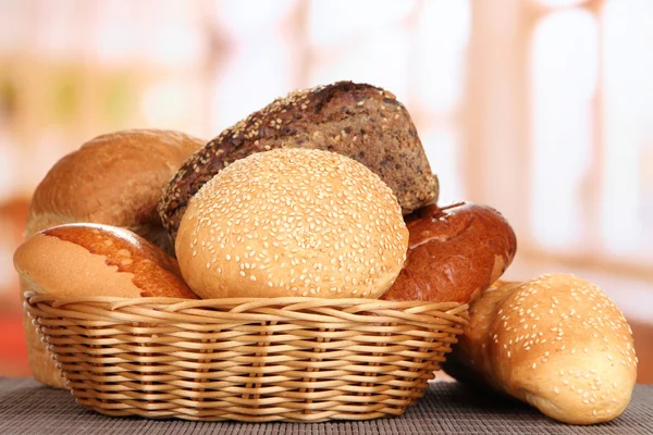 Baked bread in wicker basket on window background — Stock Photo, Image