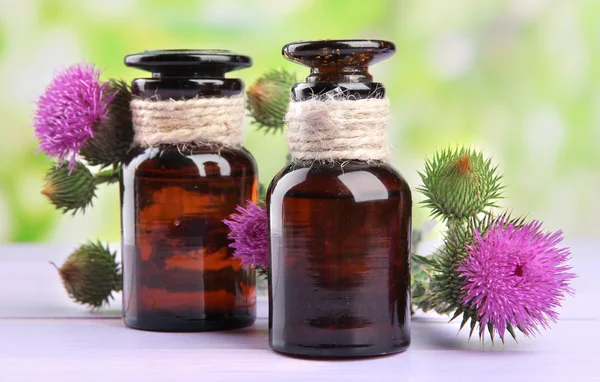 Garrafas de medicina com flores de cardo no fundo da natureza — Fotografia de Stock