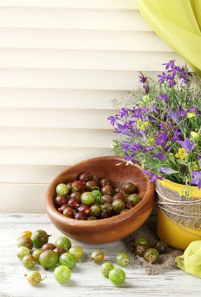 Прекрасный букет полевых цветов в чашке и ягоды на деревянном столе — стоковое фото