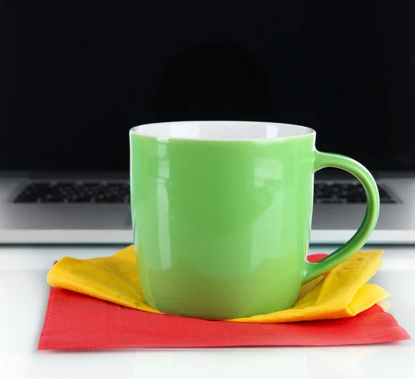 Grüne Tasse auf Serviette auf Laptop-Hintergrund isoliert auf weiß — Stockfoto