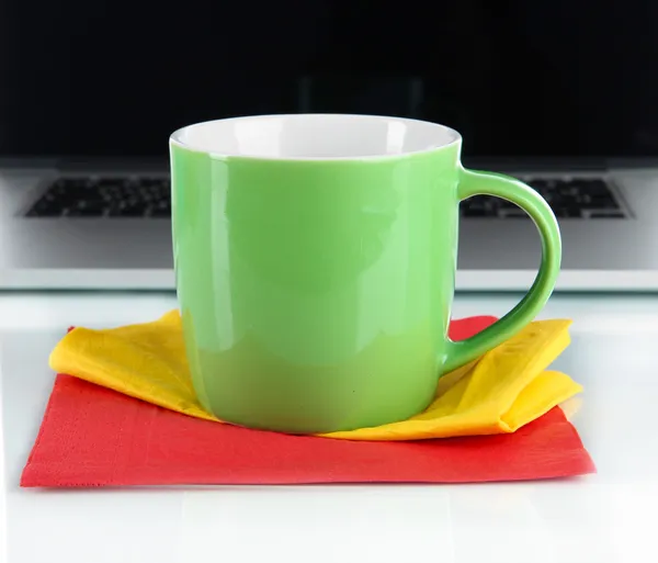 Green cup on napkin on laptop background isolated on white — Stock Photo, Image