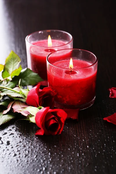 Mooie romantische rode kaarsen met bloemen op donkere houten achtergrond — Stockfoto