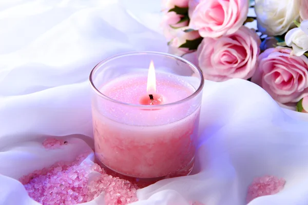 Красивая свеча с цветами на белой ткани, крупным планом — стоковое фото