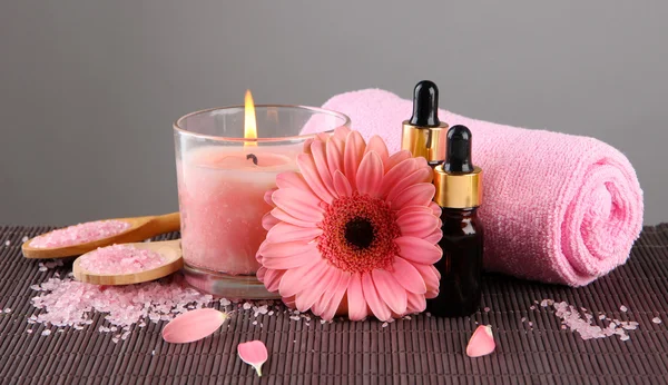 Beautiful pink candle with flower and towel on bamboo mat — Stock Photo, Image