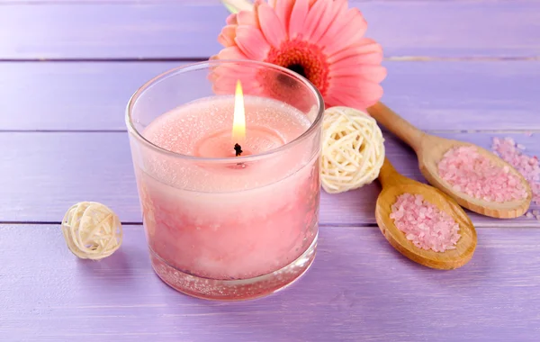 Mooie roze kaars met bloem op paarse houten achtergrond — Stockfoto