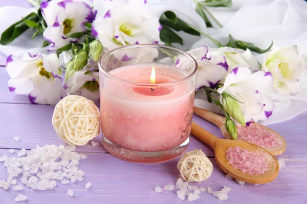 Beautiful pink candle with flowers on purple wooden background — Stock Photo, Image
