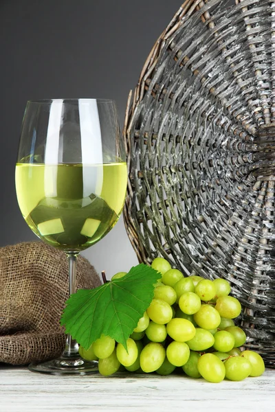 Uvas maduras deliciosas con copa de vino en la mesa sobre fondo gris — Foto de Stock