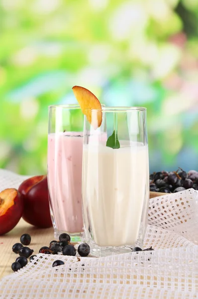 Delicious milk shakes with blackberry and peach on wooden table on natural background — Stock Photo, Image