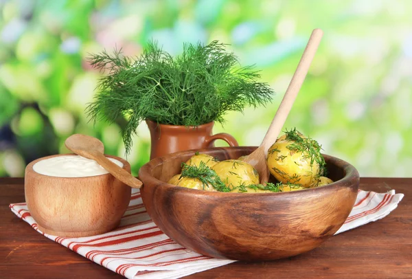 Patatas hervidas en un tazón de madera en una servilleta sobre una mesa de madera sobre un fondo natural —  Fotos de Stock